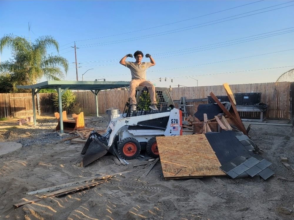 Swift Disposal crew clearing a yard with a Bobcat skid steer in Bakersfield, California